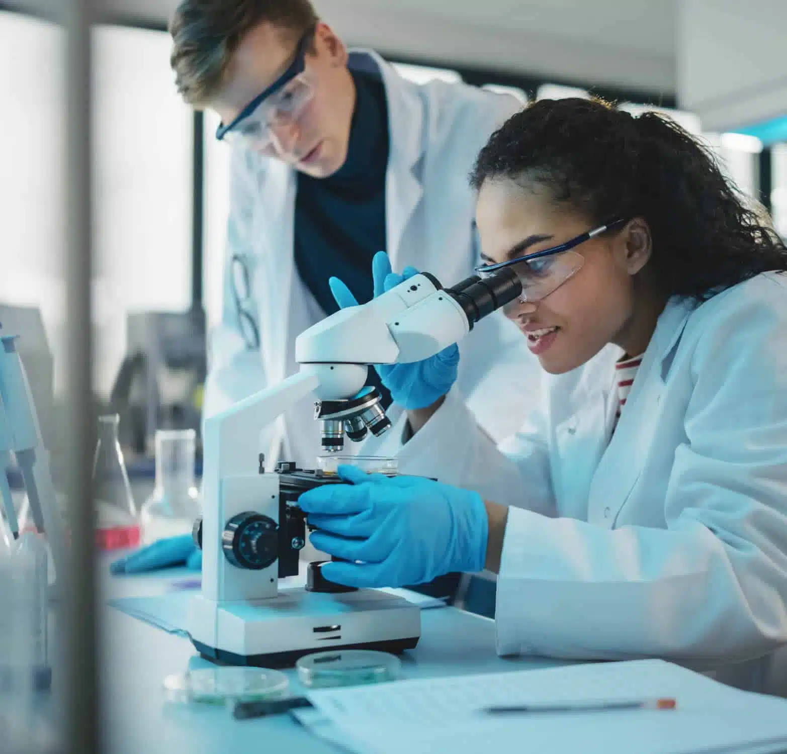 Man and woman working in laboratory looking through a microscope