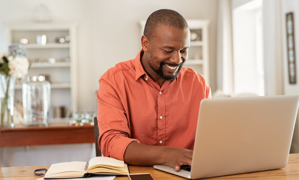 smiling man using laptop working at home