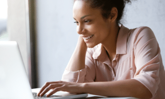 a young woman smiling and looking at laptop screen