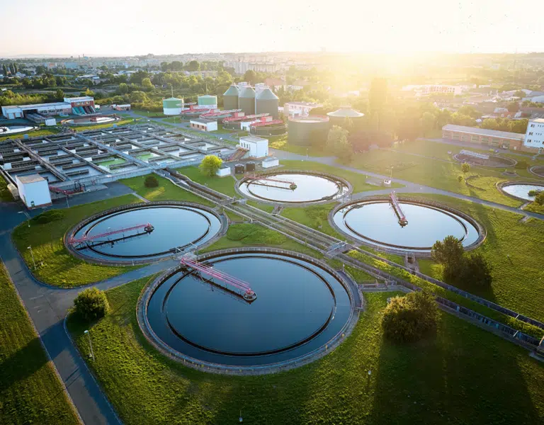 Aerial view of modern wastewater treatment plant with storage tanks in sunset.